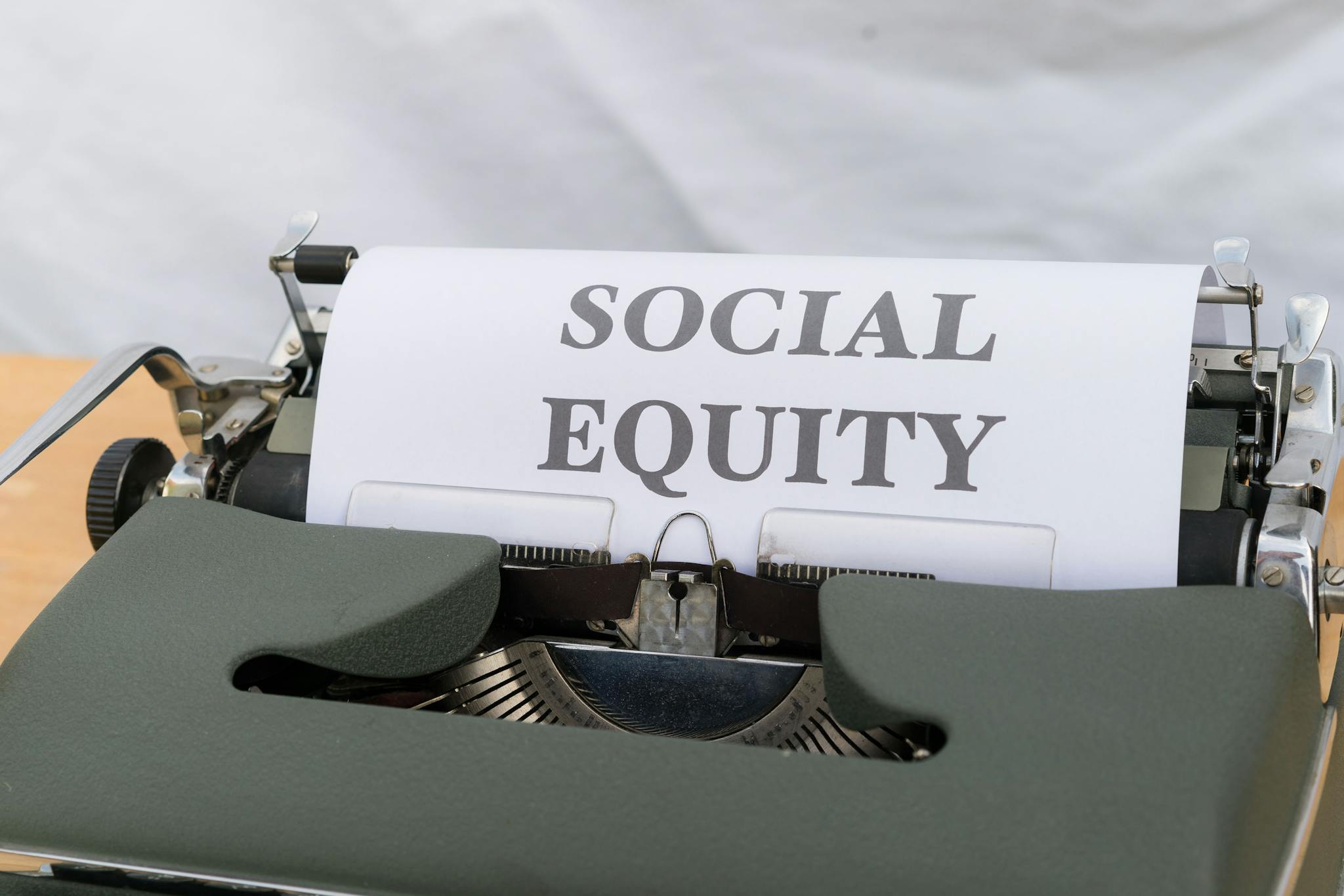Close-up of a vintage typewriter displaying the message 'Social Equity' on paper.